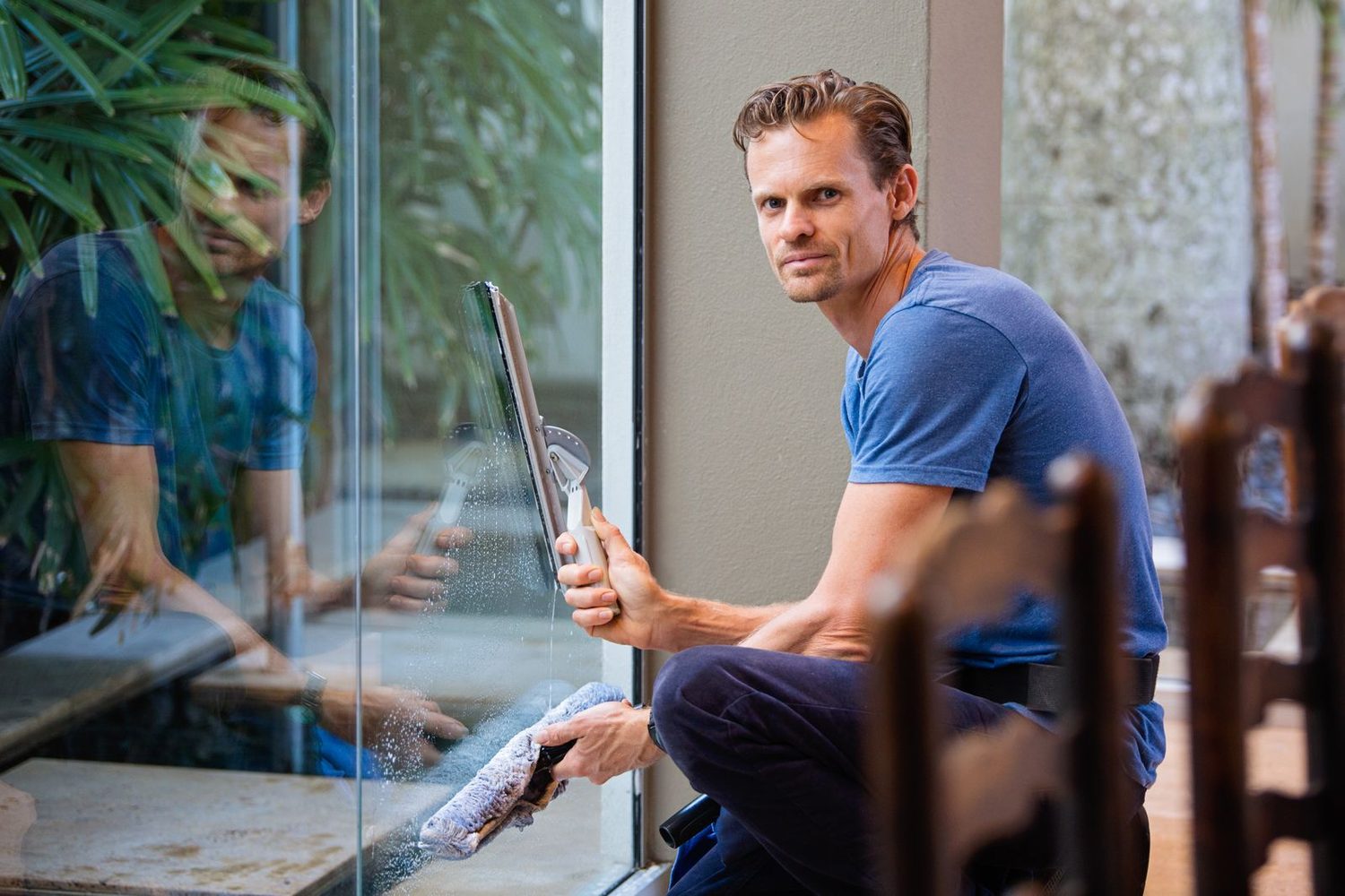 Fensterreiniger zieht mit einem Abzieher eine gro&szlig;e Glasscheibe streifenfrei ab