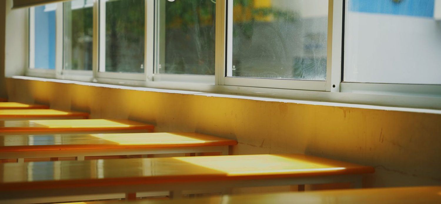 Heller, sauberer Kita-Raum mit Tischen am Fenster